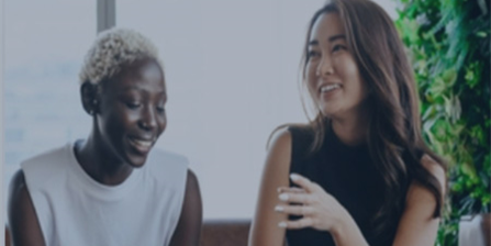 The image shows two women sitting and chatting.