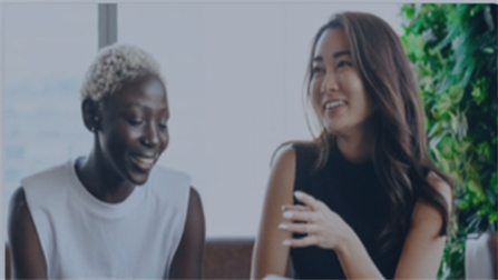 The image shows two women sitting and chatting.