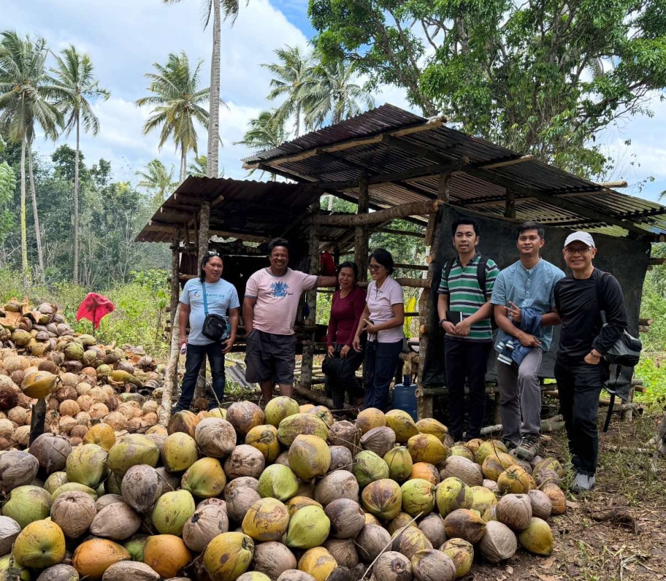 Group of people in front a bunch of coconuts