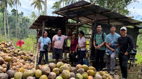 Group of people in front a bunch of coconuts